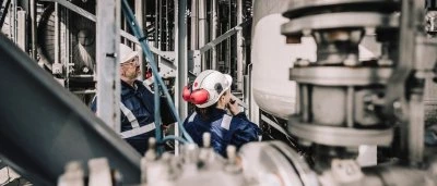 Werknemers in beschermende kleding inspecteren apparatuur in een industriële omgeving.