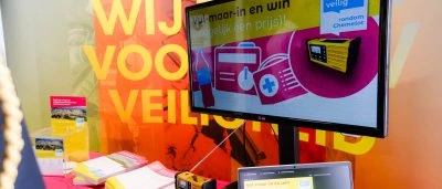 Stand met een scherm dat veiligheidsmateriaal toont en een kleurrijke achtergrond.