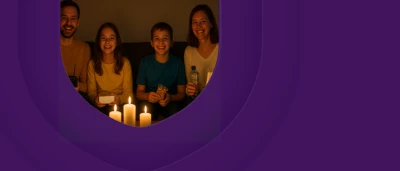 Een gezin met twee kinderen zit gezellig bij kaarslicht.