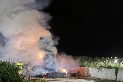Vlammen en rook stijgen op in de duisternis, bij een brand op een bouwplaats.