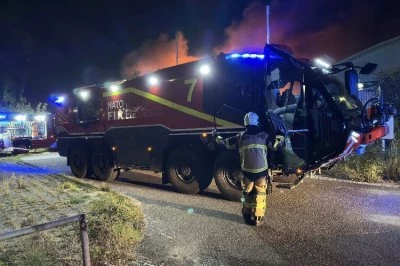 Brandweerwagen met lichten, brandweerman in gele uitrusting, nachtelijke brandachtergrond.