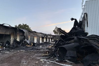 Verwoeste gebouwen na een brand, met roet en puin verspreid over de grond.