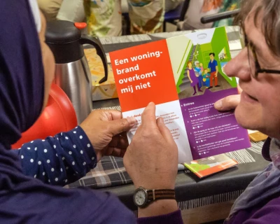 Twee vrouwen bekijken samen een brochure, met kleurrijke achtergronden en gezellige sfeer.
