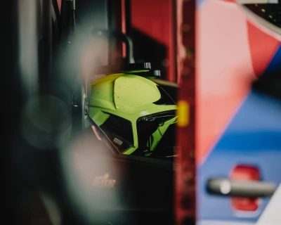 Een gedeeltelijk zichtbare brandweerhelm en blusvoertuig