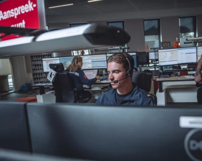 Jongeman met headset werkt geconcentreerd aan een bureau in de meldkamer.