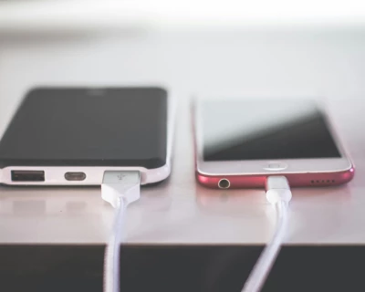 Twee smartphones met oplaadsnoeren aangesloten op een tafel.