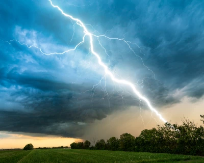 Donkere wolken met een bliksemschicht aan een bosrand