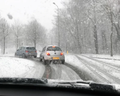 Sneeuw bedekte weg met twee auto’s die voorzichtig draaien in winterse omstandigheden.
