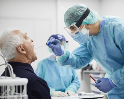 Medisch personeel in beschermende kleding neemt mond test af