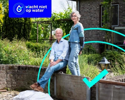 Een man en een vrouw staan op een waterbestendige dijk in een groene tuin.