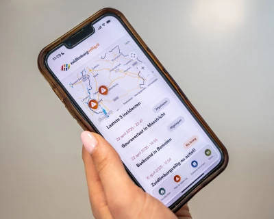 Een hand houdt een smartphone vast met een kaart en locaties aangegeven.